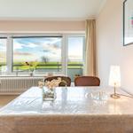 Esszimmer mit Tisch, Stühlen und Blick auf die Landschaft.