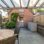Terrasse mit Pavillon, Tisch und Stühlen. Hinterhof mit Backsteinmauer und Pflanzen.