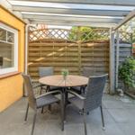 Terrasse mit Tisch und vier Stühlen unter Dach
