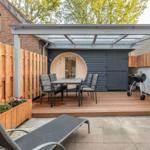Terrasse mit Sitzgruppe, Grill und Holzdecke. Runder Holzaufbau im Hintergrund.