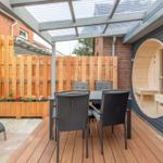 Terrasse mit Sitzgruppe, Holzdecke und runder Saunaöffnung an der Wand.