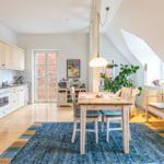 Küche mit Essbereich unter Dachschrägen. Holztisch, Stühle, Sofa und Pflanzen sind sichtbar.