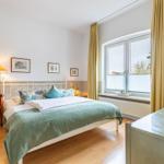 Schlafzimmer mit Bett, Holzstuhl und Fenster mit Vorhängen.