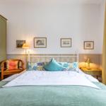 Ein Schlafzimmer mit Bett, Nachttisch, Stuhl und Kleiderschrank. An der Wand hängen Bilder.