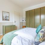 Schlafzimmer mit Bett, Kleiderschrank und Wandbild.