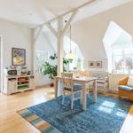Ein Esszimmer mit Holzboden, Tisch, Stühlen und einem blauen Teppich.