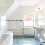 Badezimmer mit Badewanne, Toilette und Waschbecken unter Dachschräge.