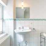 Badezimmer mit Waschbecken, Spiegel, Fenster und Handtuchhalter.