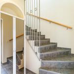 Treppe mit Steinbelag und Metallgeländer führt zur oberen Etage.