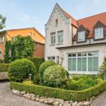 Haus mit rotem Dach, gepflegtem Garten und Kiesweg.