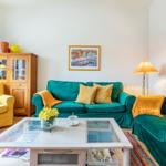Ein Wohnzimmer mit grünen Sofas, einem gelben Sessel und einem Glas-Tisch.