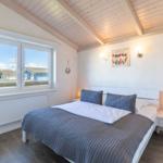 Schlafzimmer mit Doppelbett, Fensterblick und Holzdecke.