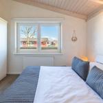 Schlafzimmer mit Bett, Fenster und Kleiderschrank. Blick auf rote Häuser.