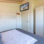 Schlafzimmer mit Bett, Kleiderschrank und Wandbild. Wand mit Aufschriften.
