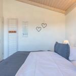 Schlafzimmer mit Bett, Wanddekoration und Holzdecke.