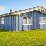 Blau gestrichenes Haus mit grünem Rasen und weißen Fenstern.