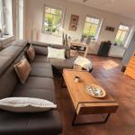 Wohnzimmer mit Ecksofa, Holztisch und Terrasse. Küche im Hintergrund.