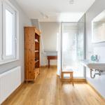Bathroom with shower, sink, and wooden cabinet against the wall.