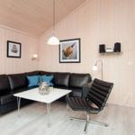 Wohnzimmer mit Ledersofa, Tisch und Stuhl. Holzwände und -decke. Wandlampen und Bilder.