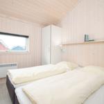 Schlafzimmer mit Bett, Fenster, Kleiderschrank und Wandregal.