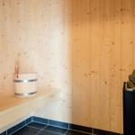 Sauna mit Holzwand, Sitzbank, Eimer und Holzstapel