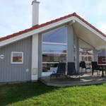 Haus mit Terrasse, Sitzgelegenheiten und Garten. Hausnummer 132. Dach mit roten Ziegeln.