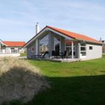 Moderne Villa mit Terrasse, Garten und rotem Dach. Sicht auf Nachbarhäuser.