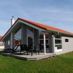 Moderne Villa mit Terrasse, Tisch und Stühlen, rotem Dach und grünem Rasen.