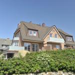 Haus mit Balkon und Blumenbeet im Vorgarten