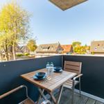 Terrace with table, chairs, and view of houses and trees.