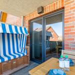 Terrace with beach chair, table, and chairs. Glass door leads into the house.