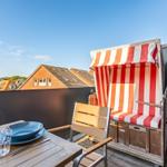 Terrace with beach chair, table and chairs. View of rooftops and sky.