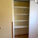 Leerer Schrank mit weißen Regalen und Schiebetüren in einem Zimmer.