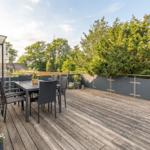 Terrasse mit Tisch und Stühlen, Pflanzen und Blick auf Bäume.