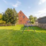 Rotes Haus mit Spielplatz und Grünfläche im Hintergrund.