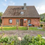 Ein rotes Backsteingebäude mit Dach und Garten.
