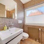 Badezimmer mit Waschbecken, Toilette und Spiegel an der Wand.