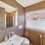 Badezimmer mit Waschbecken, Spiegel, Toilette und Fenster.