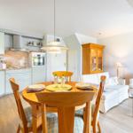 Kitchen with dining table, living room with sofa and glass table.