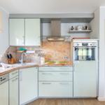 Kitchen with light cabinets, stone countertop, and built-in oven.