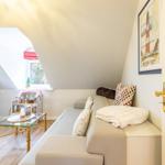 Living room with sofa, TV, and dollhouse under sloped ceiling.