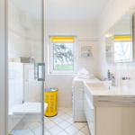 Bathroom with shower, sink, and window to the garden.