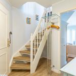 House with staircase, glass railing, and adjacent rooms.