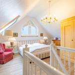 Bedroom with sloped ceiling, bed, wardrobe, and seating area.