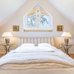 Bedroom with sloped ceiling, bed, window, and nightstands