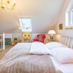 Bedroom with sloped ceiling, bed, armchair, and windows