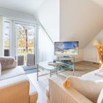 Living room with sofa, TV, and terrace. Dining area with wooden table.