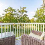 Terrace with wicker furniture and view of green trees.