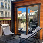 Terrace with two lounge chairs and glass doors to the garden view.