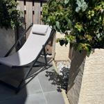 Lounger on terrace between plants and stone walls.
